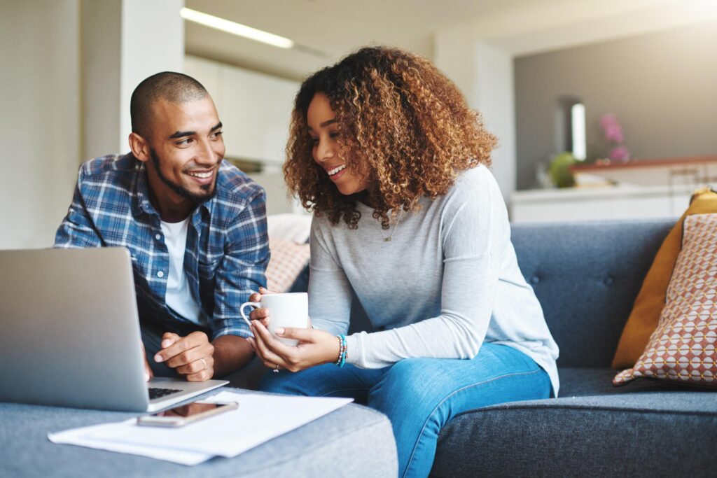 Happy couple discussing finances while looking at laptop