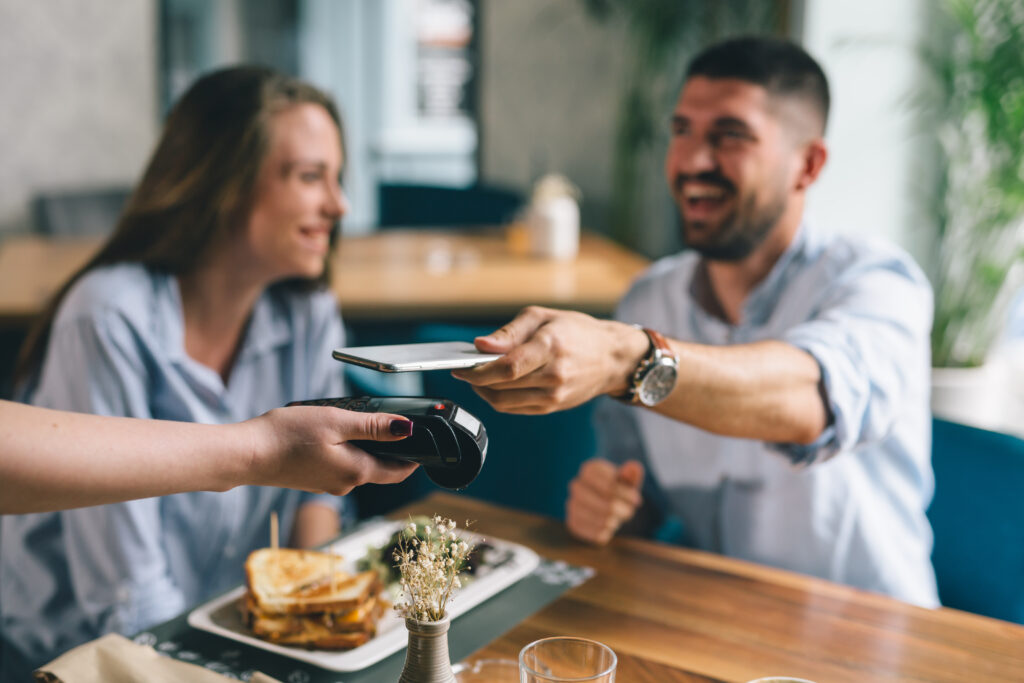 man paying contactless with mobile phone in restaurant