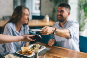 man paying contactless with mobile phone in restaurant
