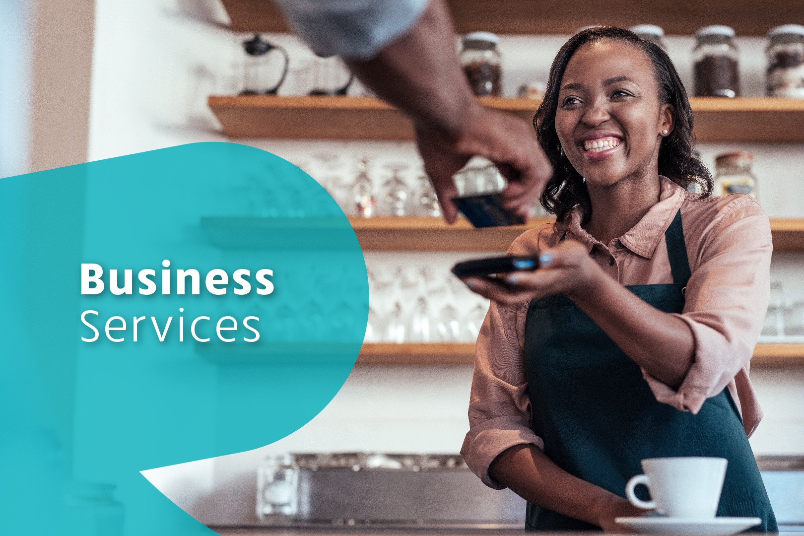 Photo of smiling cashier at a coffee shop accepting payment from a customer via tap-to-pay. Business Services