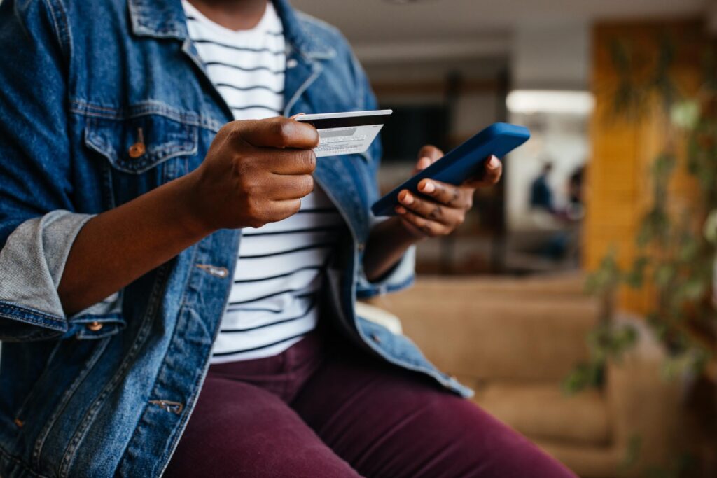 Woman holding phone and debit card.