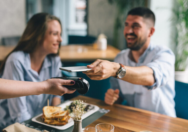 man paying contactless with mobile phone in restaurant