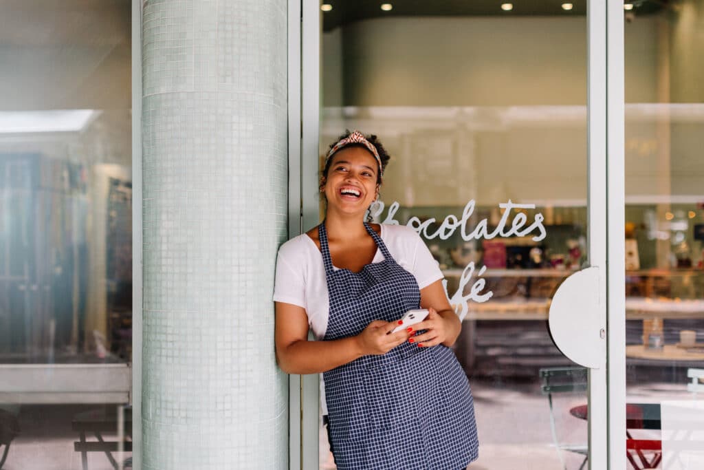 female business owner standing in front of cafe door