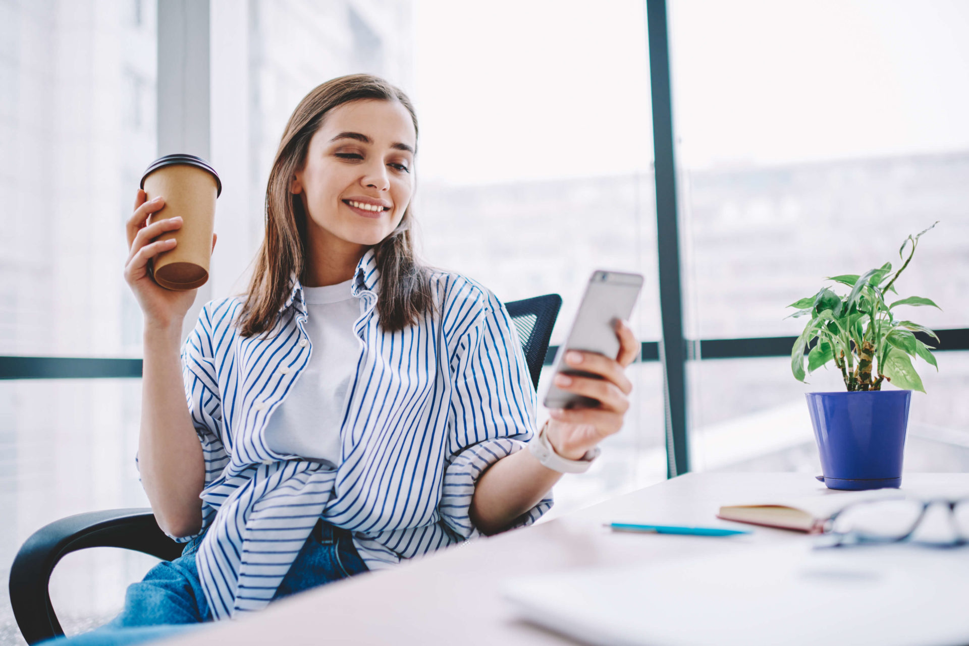 girl looking at phone while sitting at a desk