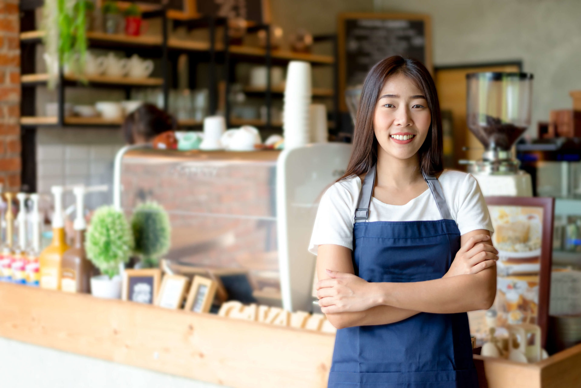 young barista wearing an apron standing in coffee shop