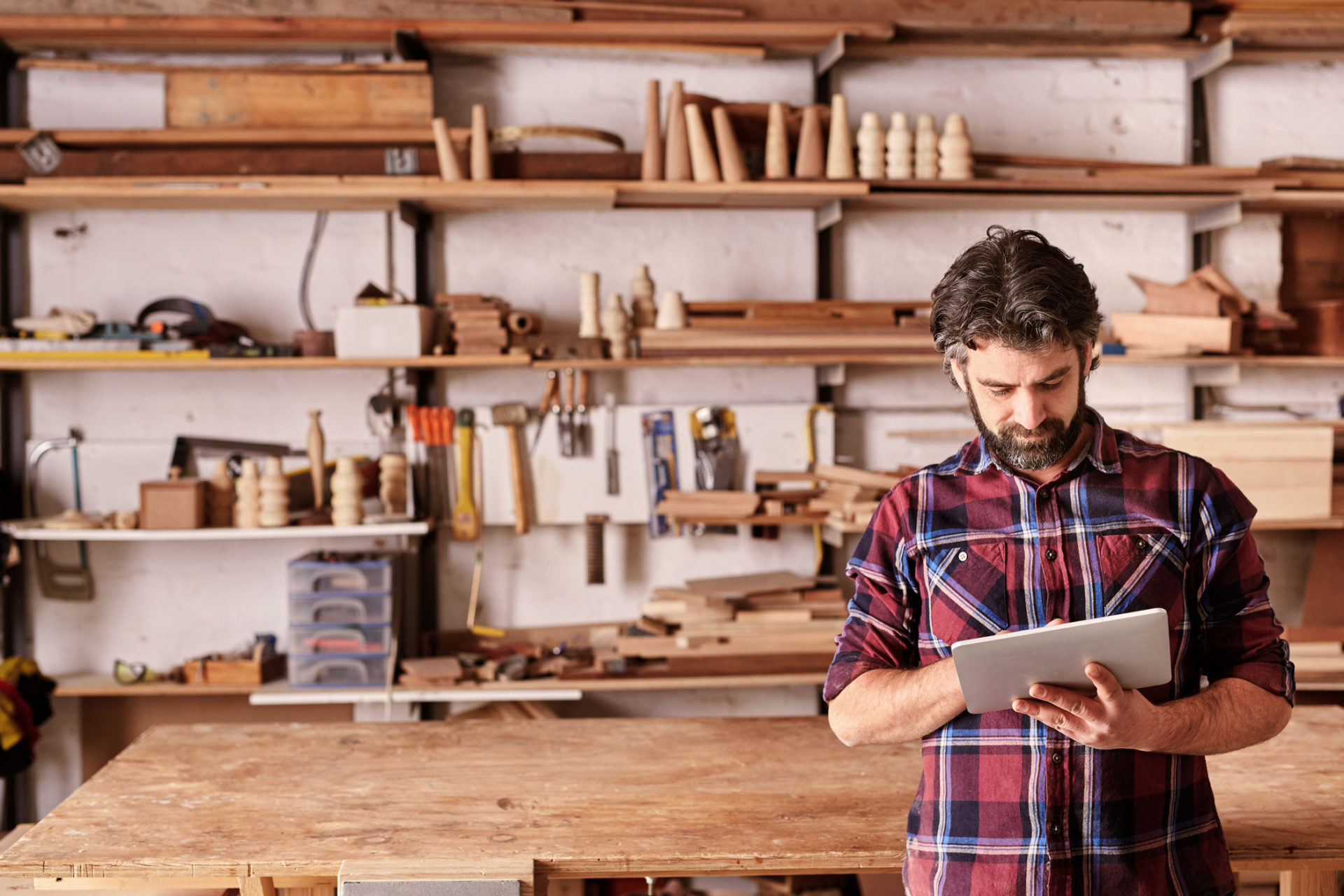 man-holding-tablet-in-woodshop
