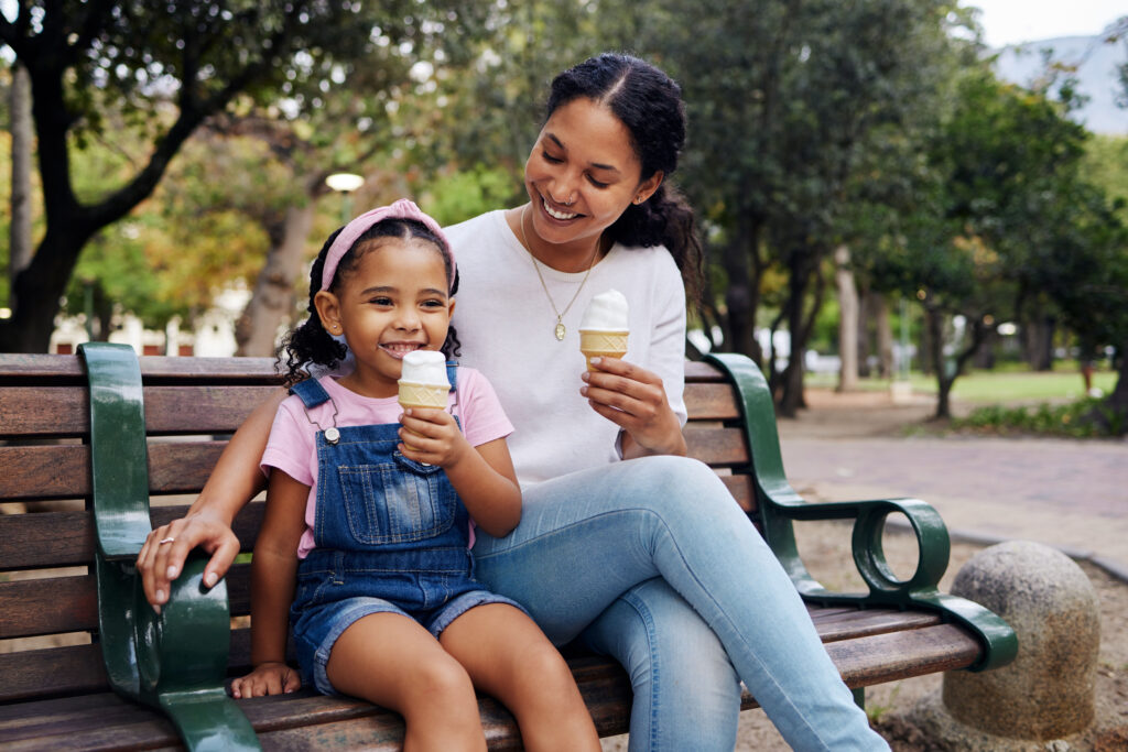 Mother and daughter on a park bench enjoying ice cream cones