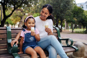 Mother and daughter on a park bench enjoying ice cream cones